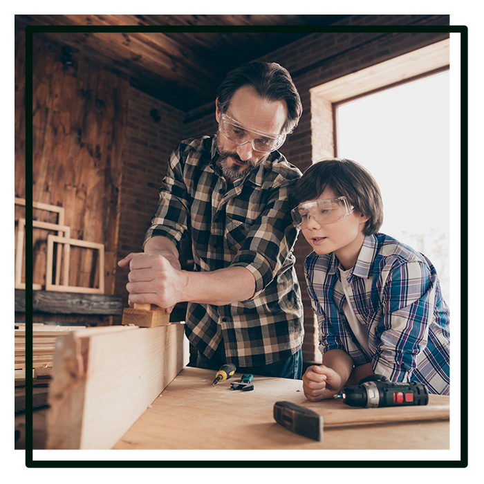 Father teaches son woodworking in a workshop